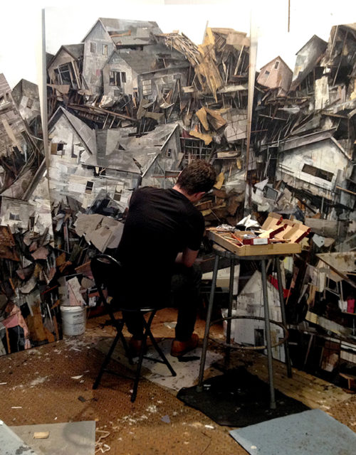 A man painting fragmented houses on a wall