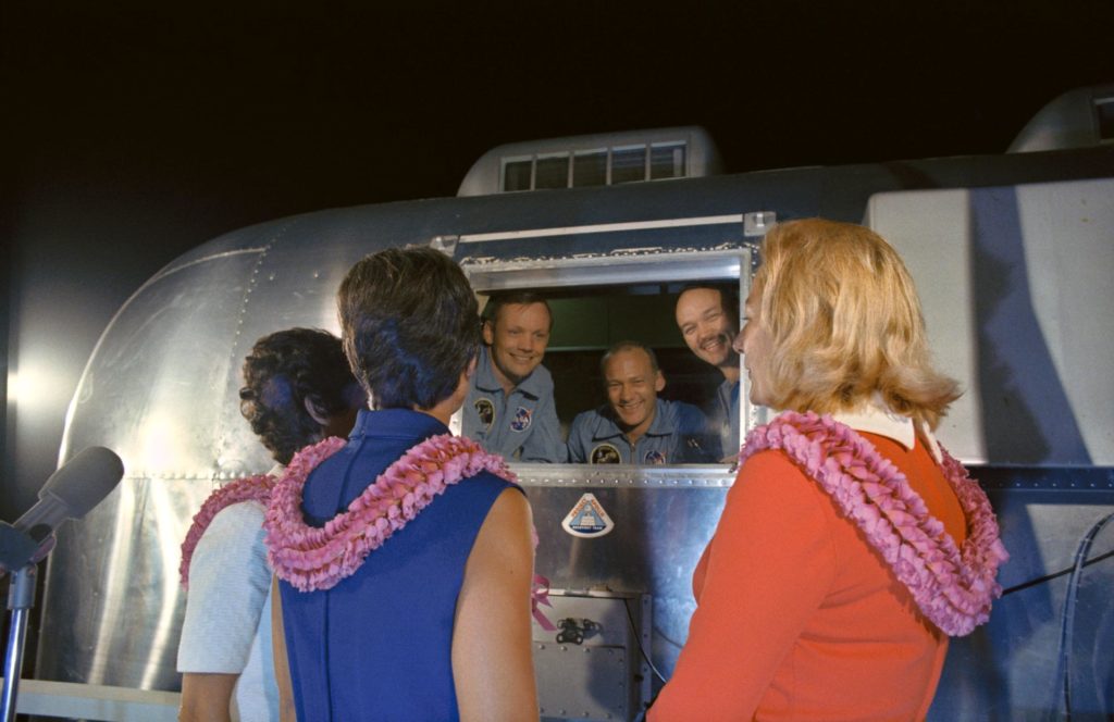 The Apollo 11 crewmen, still under a 21-day quarantine intended to protect the planet from backward contamination, are greeted by their wives.