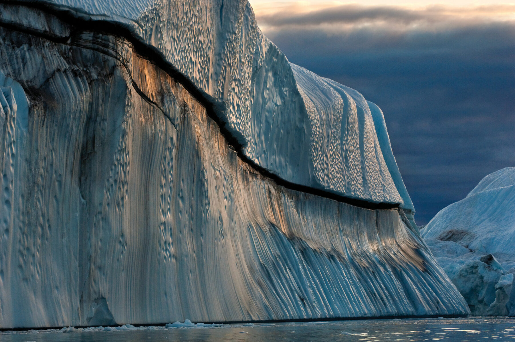 James Balog, Copper Berg, Jakobshavn Isbræ, Greenland, August 24, 2007. Icebergs that have rolled over and been scalloped by waves metamorphose into fantastic shapes.