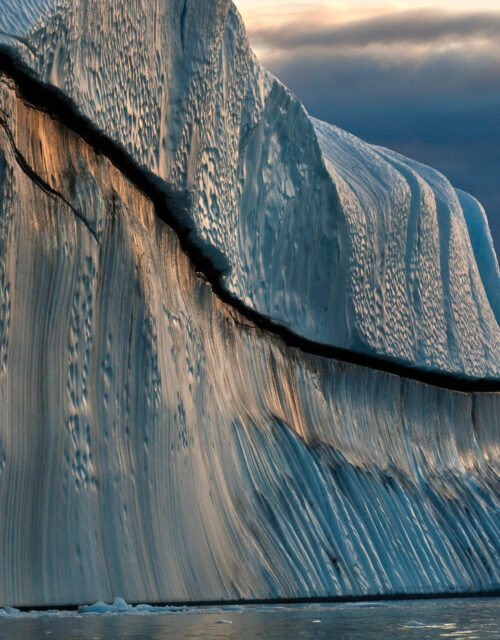 James Balog, Copper Berg, Jakobshavn Isbræ, Greenland, August 24, 2007. Icebergs that have rolled over and been scalloped by waves metamorphose into fantastic shapes.