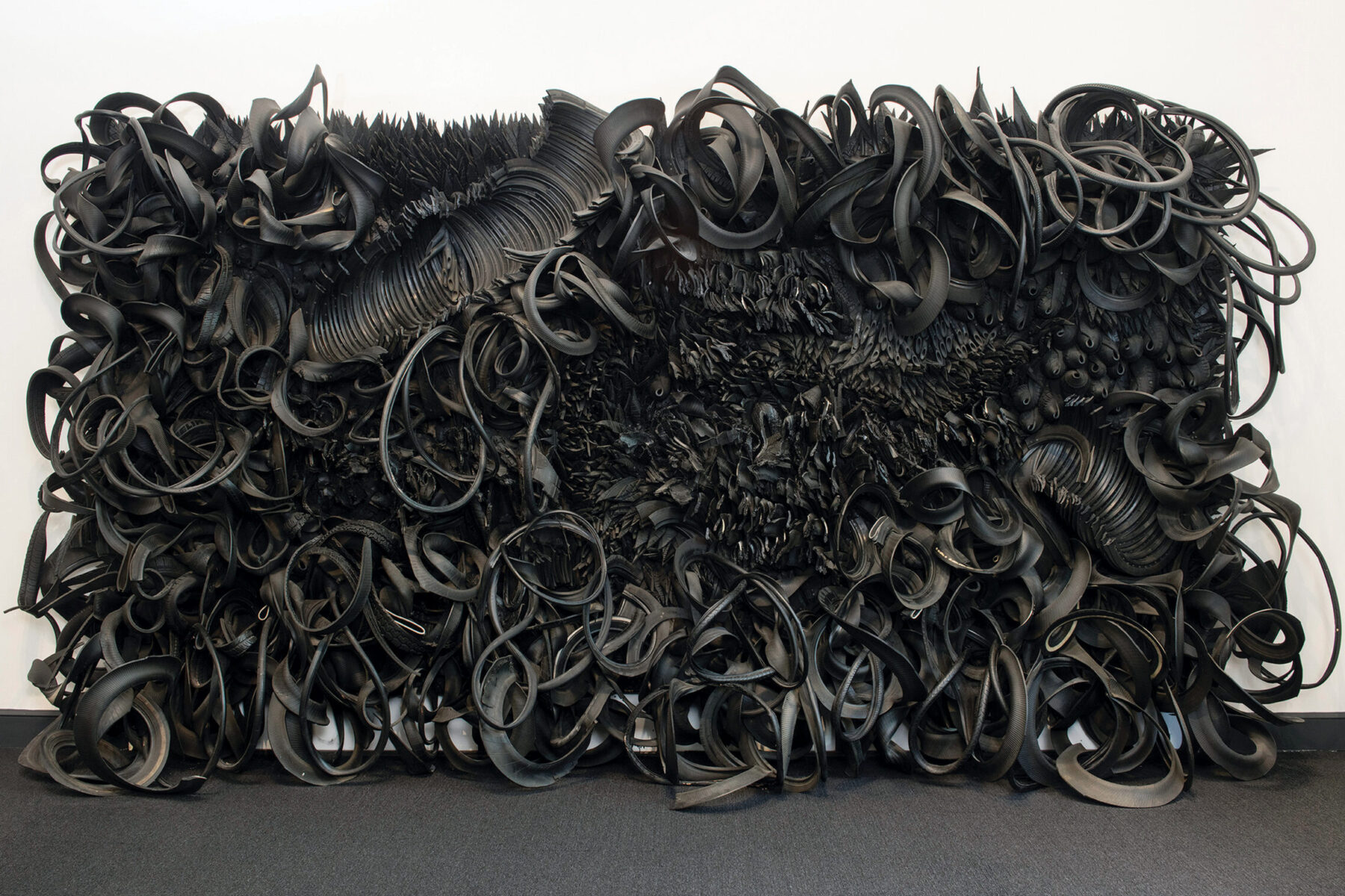 Chakaia Booker, Acid Rain, 2001, rubber tires and wood, overall: 120 x 240 x 36 inches; each armature (3 total): 80 x 48 x 1 inches; tire pallet (12 total): 22 x 48 x 40 inches. National Museum of Women in the Arts, Washington, DC. Museum purchase: Members’ Acquisition Fund © Chakaia Booker. Photo by Lee Stalsworth.