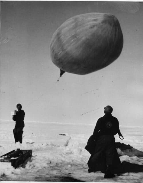 Two Scientists and a Weather Balloon on IGY Drifting Station Bravo in the Arctic Ocean, 1957. Bravo was a United States Arctic drifting station on a large ice floe where scientists gathered data about ocean currents, ice movement, and weather conditions. Image courtesy National Academies Archives.